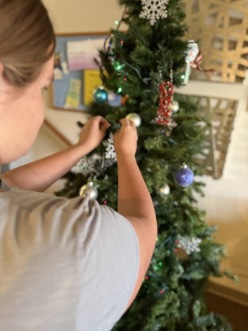 A young woman hanging an ornament on a holiday tree