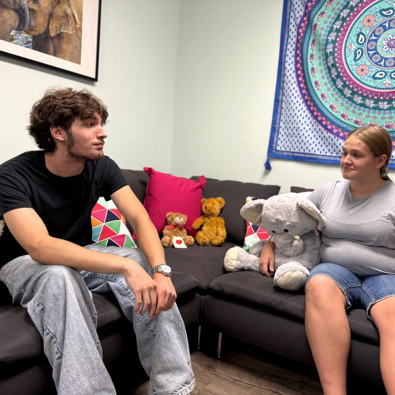Two teens talking on the couch in the teen room